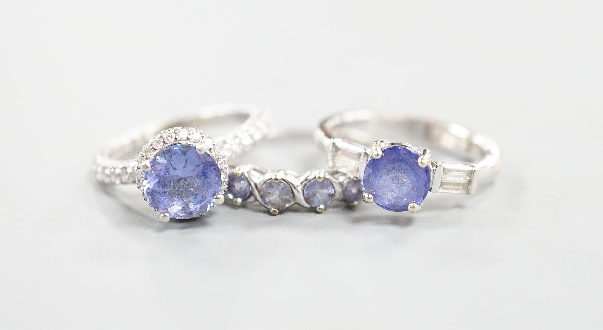 Two modern 18k white metal, tanzanite and diamond set dress rings, size J, gross 8.3 grams and a modern 9ct white gold and gem set ring, gross 2 grams.